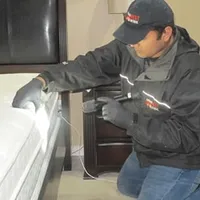 Bed bug inspection technician checking a mattress and bed frame for signs of infestation in Jacksonville, FL